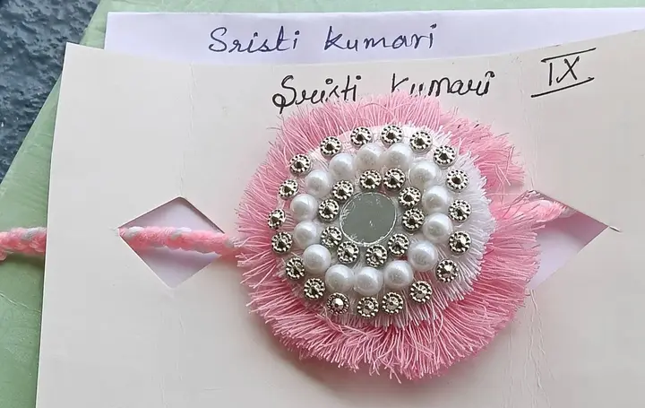 A pink and pearl handmade rakhi