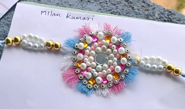 A handmade rakhi with pearls and mirror work