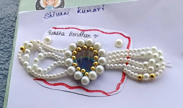 A pearl rakhi with a peacock feather centre