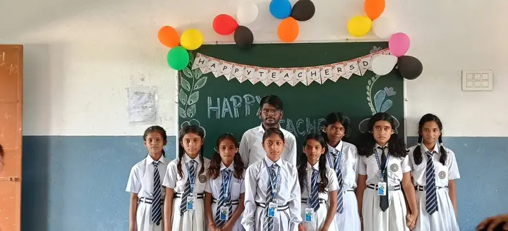 Students and teacher pose in a decorated classroom