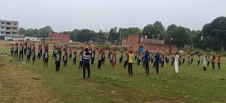 Students practise yoga on the school ground with the school building behind
