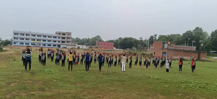 Rows of students stand in a yoga pose on the school ground